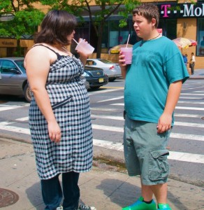 two overweight teens drinking milkshakes